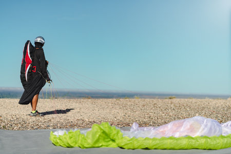 Paraglider in professional flight suit and helmet looking into the sky at the top of a hill ready to take off. Copy space for advertisement or text on right sideの写真素材