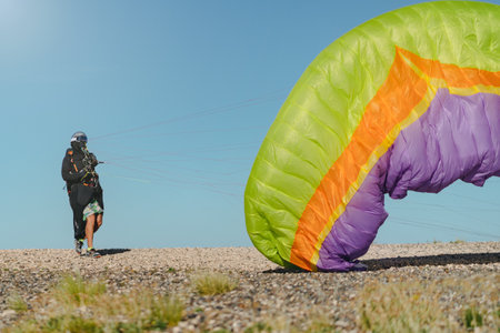 Professional sports man taking ropes and paraglider up for flight on a sunny dayの写真素材