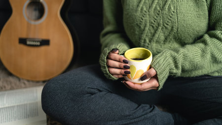 Cozy winter concept. Woman wearing knitwear at home while drinking coffee and reading a book alone. Close up shot. unrecognizable personの写真素材