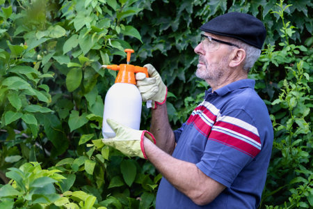 Mature man holding bottle of sprayer for fertilizing his plants. Retirement and leisure activities conceptの写真素材