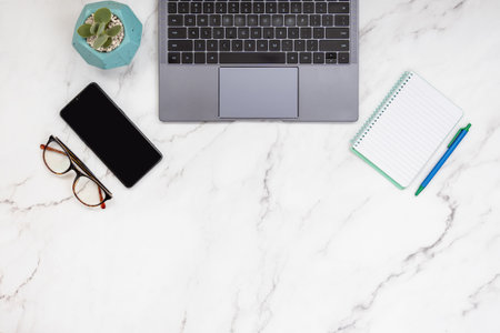 Minimal desk top view of small business with keyboard of laptop, smart phone, note pad, eyeglasses...