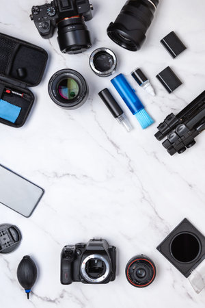 White marble desk top view of cameras cleaning kit with digital cameras, lenses, brushes, filters. Copy space in the middleの写真素材