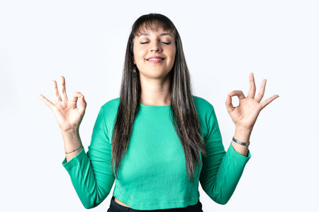 Hispanic brunette woman doing Zen gesture over white background. Healthy lifestyle and mindfulness concept.の写真素材