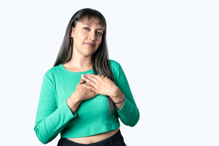 Latin woman wearing green blouse smiling with hands on chest with grateful gesture on face and looking at camera. White isolated background slow motion videoの写真素材