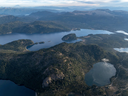 Aerial view of Alumine Lake and small 4 lagoons, surrounded by forested hills and Andean mountain range visible in the distance. Villa Pehuenia, Neuquen, Argentinaの写真素材