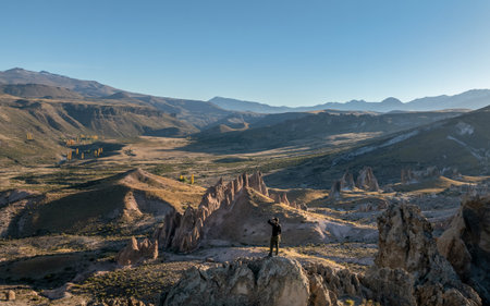 Man stands on a rocky outcrop overlooking the dramatic rock formations of Los Bolillos, North of Neuquen province, Argentinaの写真素材