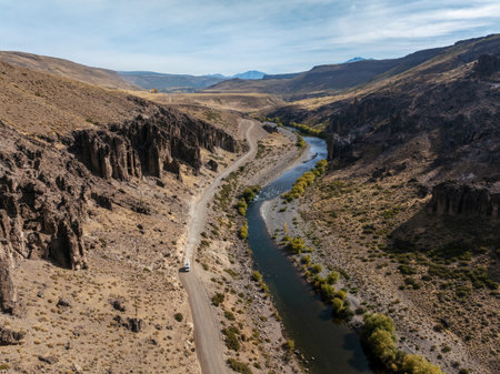 Aerial view captures Varvarco road and Neuquen river winding through a valley landscape. Argentina, South Americanの写真素材