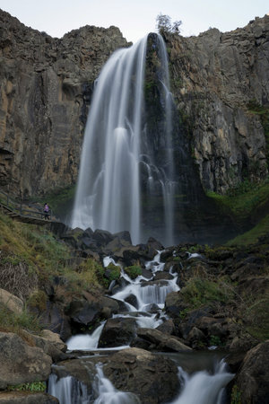 Majestic La Fragua Waterfall, crystal clear waters tumble over rocks, with people in the distance...