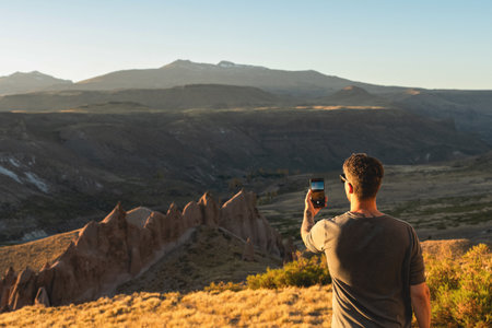Man photographs the scenic landscape of Los Bolillos rock formations with his smartphone. Neuquen, Argentinaの写真素材