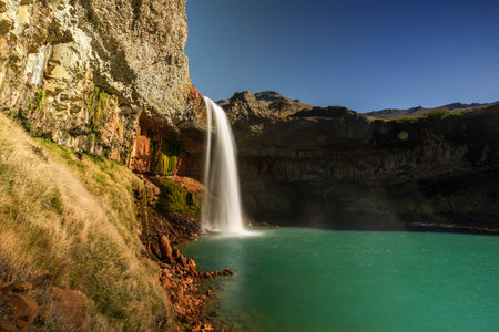 El Saltpo del Agrio waterfall cascading on turquoise water lagoon with epic colorful rock formations. Neuquen, Patagonia, Argentinaの写真素材
