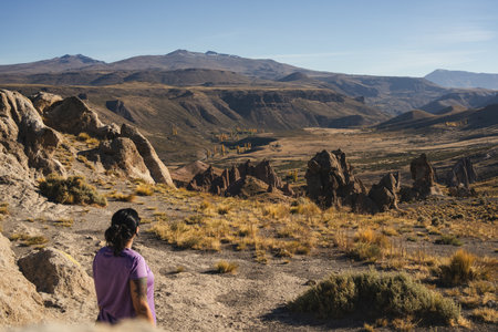 Woman at the unique rock formations of Los Bolillos, Neuquen, Argentina, under a clear sky with mountains in the distanceの写真素材