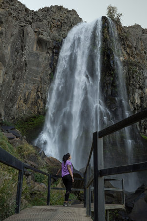 Woman admiring La Fragua Waterfall: Sparkling water hits mossy rocks, forming a natural pool. Manzano Amargo, Neuquen tourist destination, Argentinaの写真素材