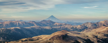 Panoramic view of Lanin volcano mountain rising above a rugged, mountainous landscape under cloudy sky in Patagonia. Los Andes mountains range in the distanceの写真素材