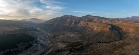 Aerial panoramic view of Neuquen river in Patagonian valley landscape under sunbeam of a cloudy sky. Autumn season in Manzano Amargo, Neuquen, Argentinaの写真素材