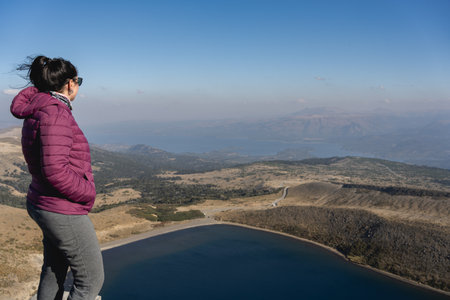 Woman looks out over Batea Mahuida lake and the surrounding landscape from an elevated viewpoint. Villa Pehuenia, Neuquen, Argentinaの写真素材