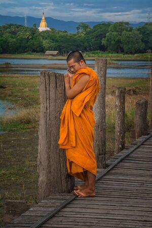 On U Bein Bridge in Amarapura. Young Monk Talked to her mobile. U Bein Bridge is a passage That crosses the lake near Taungthaman Amarapura Myanmar. 7th August 2014のeditorial素材