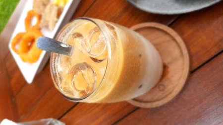 Iced coffee with milk in a glass on the wooden table.の写真素材