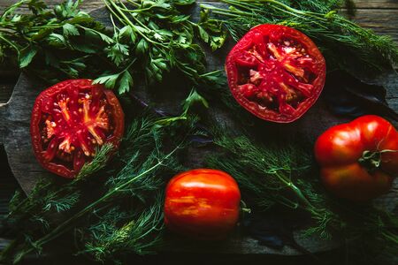 Fresh tomatoes on a dark background. Tomatoes, parsley, dillの写真素材
