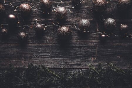 Christmas or New Year background. Vintage Christmas tree toy decoration balls and light garland over rustic wooden background, selective focus, copy spaceの写真素材
