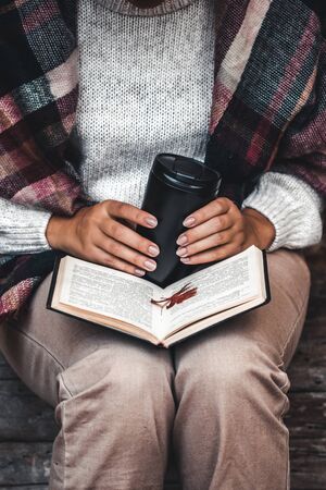 Autumn concept, an open book in the hands of a girl with yellow leavesの写真素材