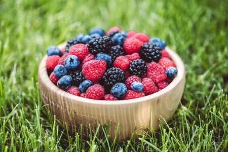 raspberries and blackberries in wood bowl on table, vintageの写真素材