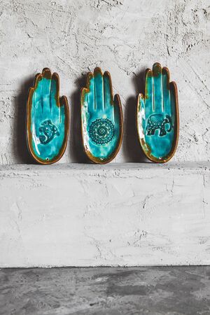Unusual turquoise plate in the shape of a hand on a gray background. Ethnic themeの写真素材