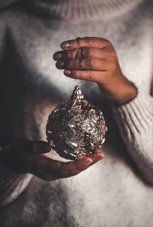 Woman in warm sweater holding toy glass decorative ball in hands, copy space. Christmas, new year holiday celebration conceptの写真素材