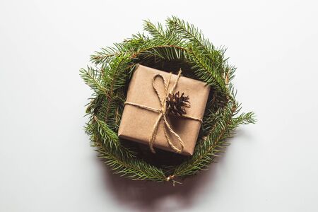 Gift in craft paper in a wreath of Christmas trees. Christmas mood, New Year, On white backgroundの写真素材