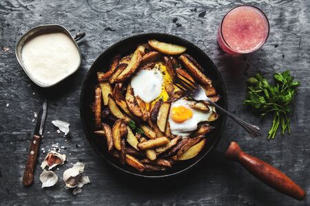 Fried potatoes with meat, ham and eggs in a pan close-up. horizontalの写真素材