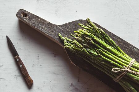 asparagus on a cut board on an old white backgroundの写真素材