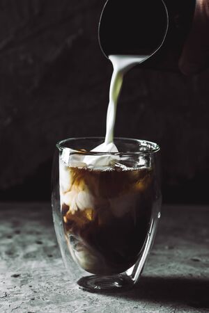 The moment pouring milk into coffee.の写真素材