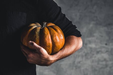 Man holding ripe pumpkin in hands on a gray backgroundの写真素材