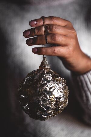 Woman in warm sweater holding toy glass decorative ball in hands, copy space. Christmas, new year holiday celebration conceptの写真素材