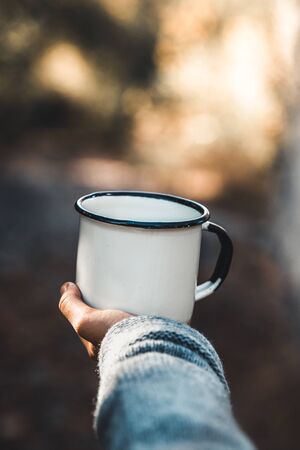 hand holding cup of coffee on natural backgroundの写真素材