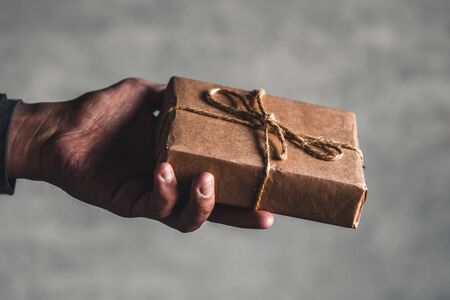 female hand hold gift box wrapped with craft paper