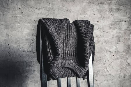 Knitted gray sweater on the back of a white wooden chairの写真素材