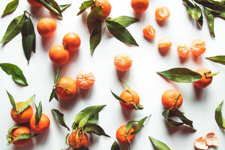 Oranges fruits composition with green leaves and slice on white wooden background, top view