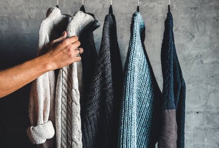 Collection of warm sweaters hanging on rack against graybackground, closeupの写真素材