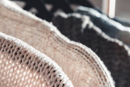 Collection of warm sweaters hanging on rack against graybackground, closeup