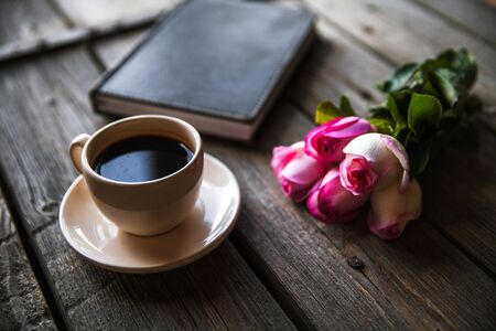 Fresh roses with diary and cup of coffee on wooden table, top view. flowers, hot drinkの写真素材
