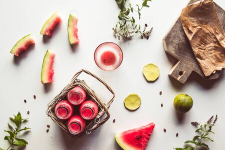 Tasty summer bottled watermelon drink in a basket and slices of fresh fruits on white backgroundの写真素材