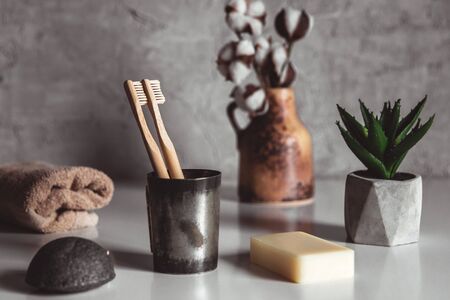 Two white and yellow eco friendly bamboo wooden toothbrushes on wooden background with white. Plastic free sustainable lifestyle symbolの写真素材
