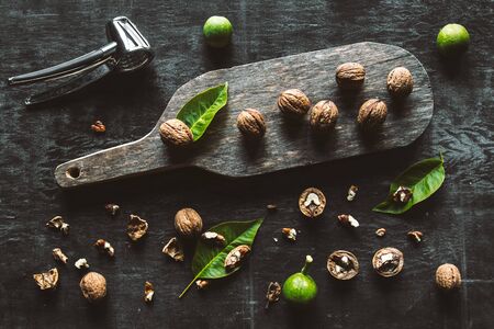 Walnuts on dark vintage table. healthy food. Nuts are scattered on a cutting board. Old vintage table and leaves from the nut.の写真素材