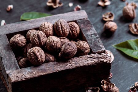 Box with tasty walnuts and nutcracker on dark wooden table, closeupの写真素材