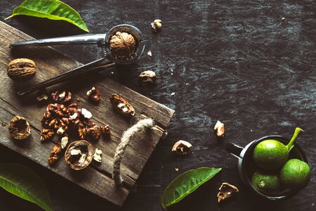 Walnuts on dark vintage table. healthy food. Nuts are scattered on a cutting board. Old vintage table and leaves from the nut.の写真素材