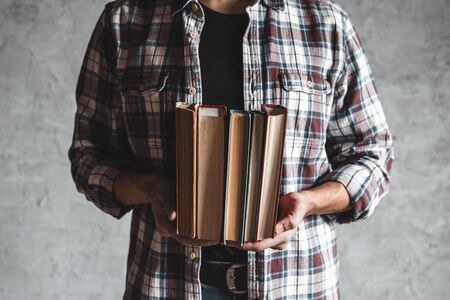 Student holding in hand a stack of old books. learning, success, knowledge