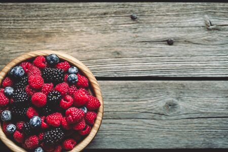 raspberries and blackberries on a wooden background in vintage style. Cutting board