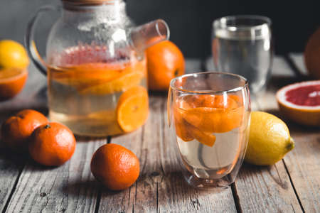 Citrus tea in a transparent teapot on a table with grapefruit and on a wooden table. Healthy drink.の写真素材