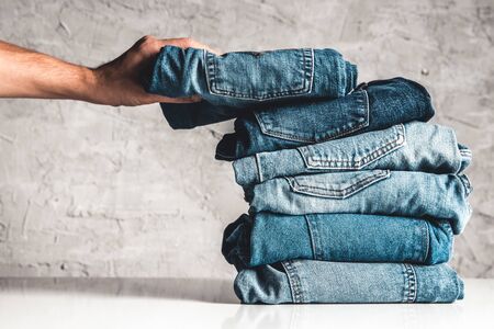 Hands, put the stack of blue jeans on gray background.の写真素材