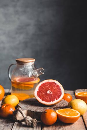 Citrus tea in a transparent teapot on a table with grapefruit and on a wooden table. Healthy drink.の写真素材